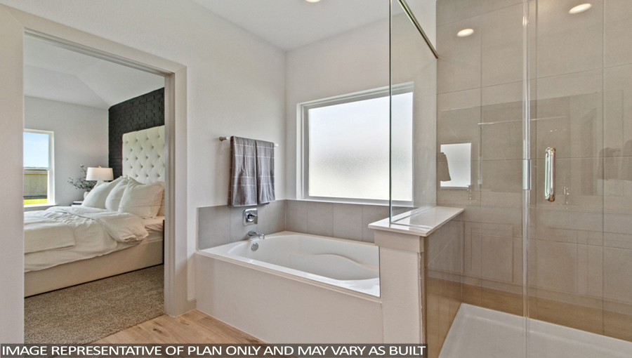Staged primary bathroom with a frosted window, a tile tub, and a standing shower with a glass door.