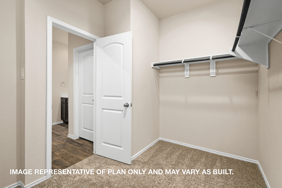 Walk-in closet with carpet flooring and overhead storage space.