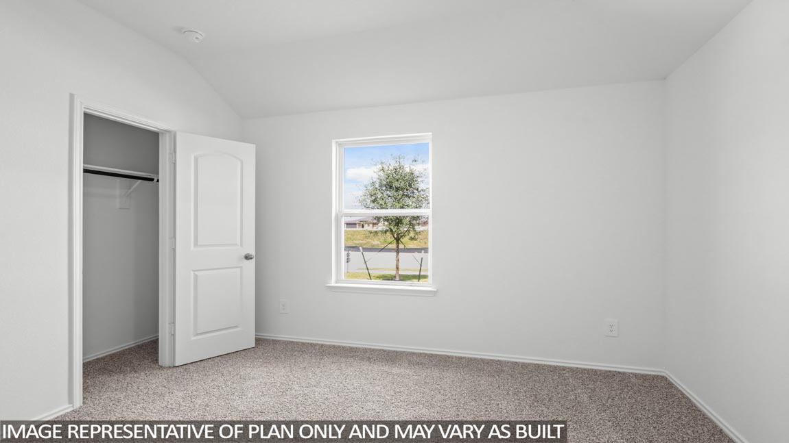 Secondary bedroom with carpet flooring, a tall closet, and a bright window.