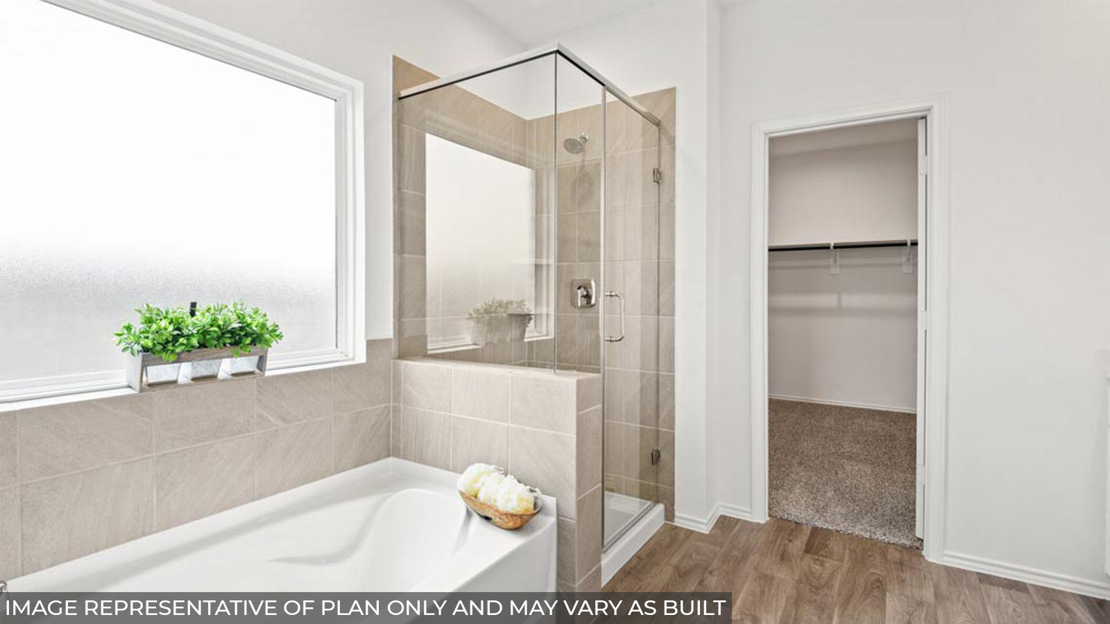 Primary bathroom with a frosted window, a tile tub, a standing shower, a separate toilet room, a walk-in closet, and a double sink.