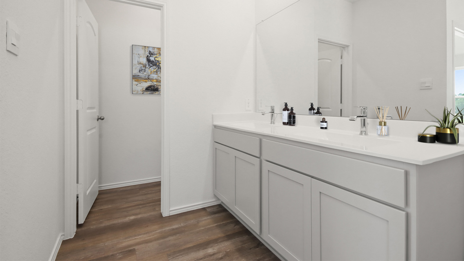 Staged primary bathroom with a double sink and a separate toilet room.