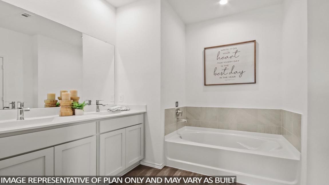 Primary bathroom with vinyl flooring, a tile tub, and a double sink.