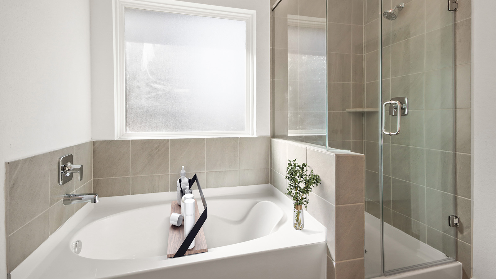 staged primary bathroom with a tile tub, a standing shower, and a frosted window