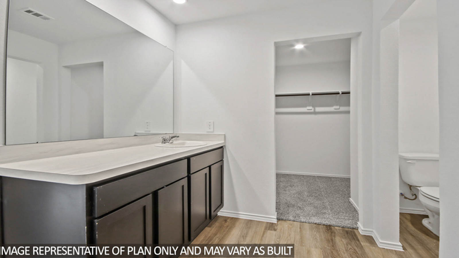 Primary bathroom with a double sink and an attached walk-in closet.