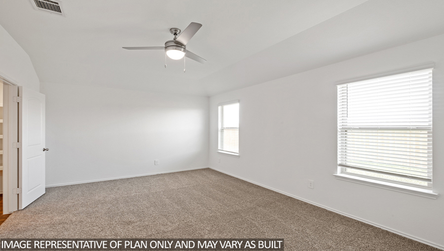 Primary bedroom with carpet flooring and bright windows.