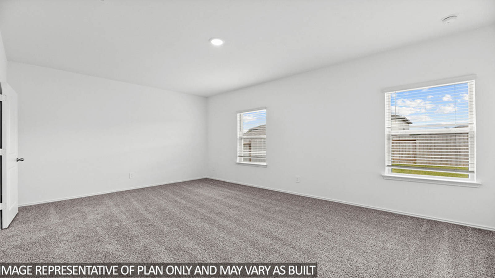 Primary bedroom with carpet flooring and two bright windows.