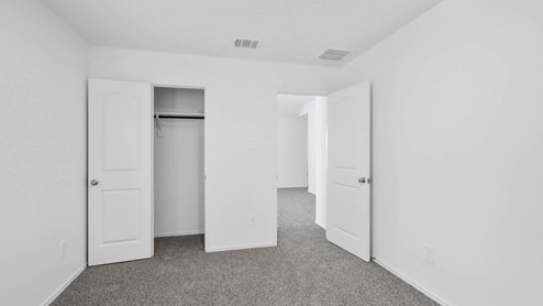 Secondary bedroom with neutral carpet and closet.