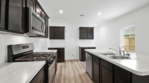 Perfect sized kitchen with white countertops and dark cabinets.