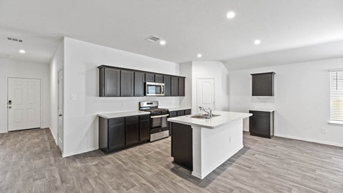 Kitchen area with dark cabinets and stainless teel appliances