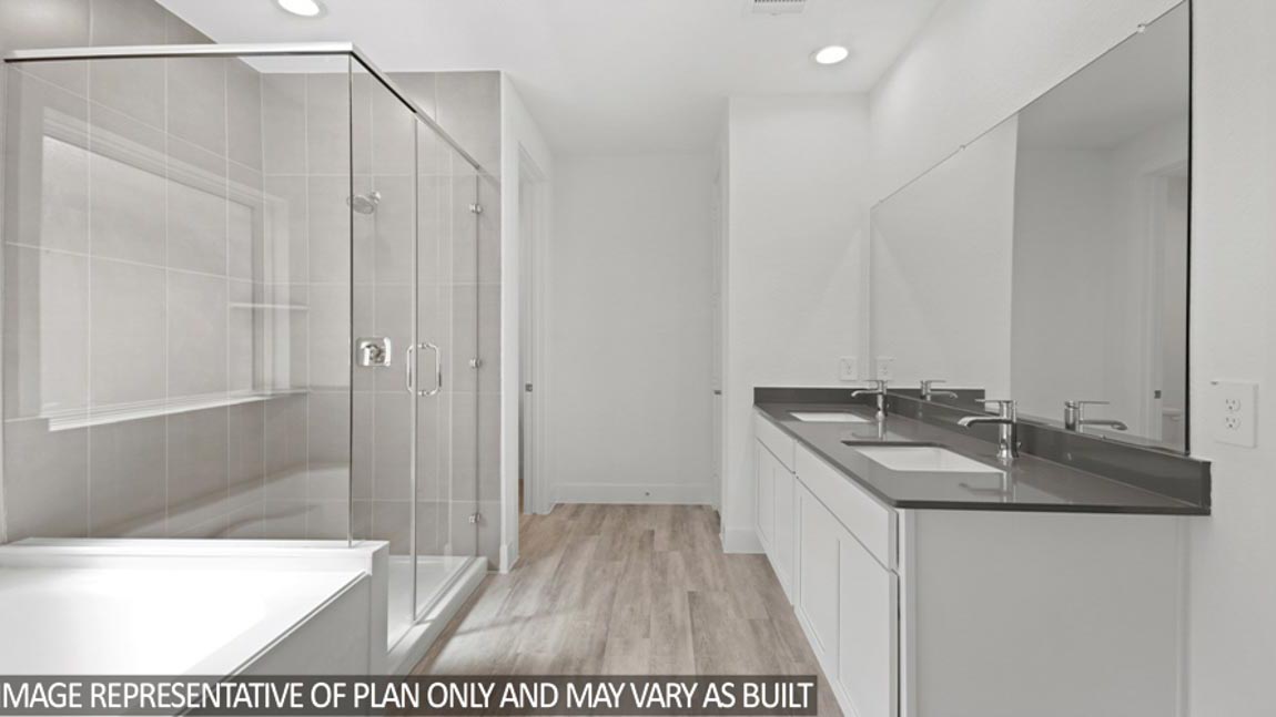 Primary bathroom with a double sink, a frosted window, a tile tub, a standing shower with a glass door, a separate toilet room, and a walk-in closet.