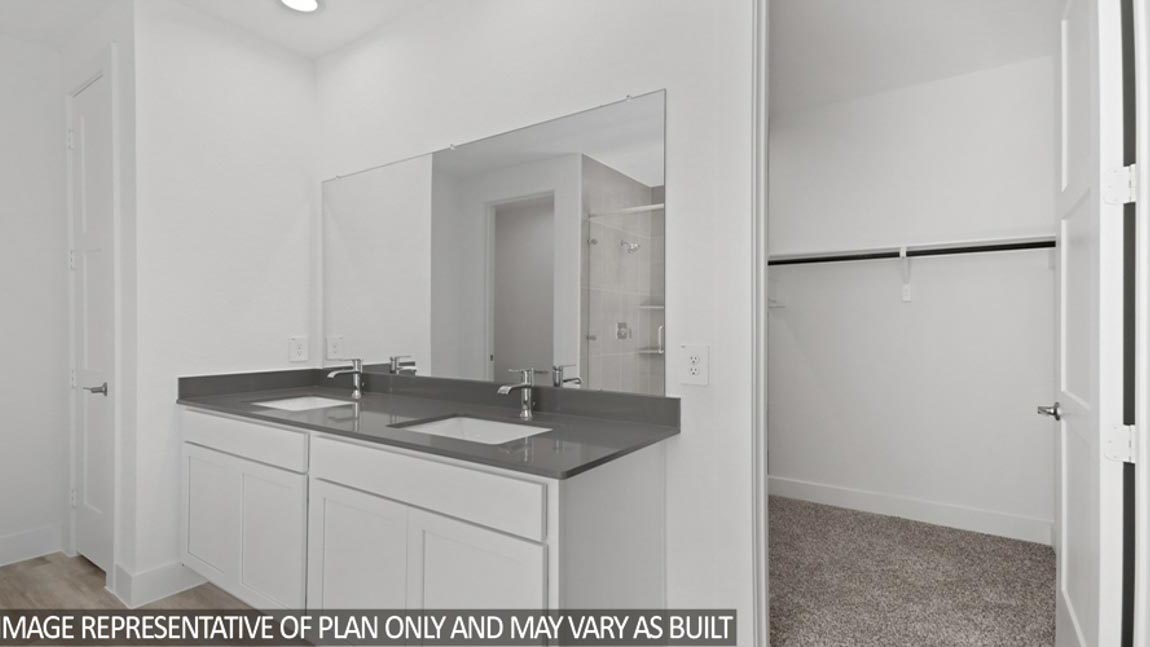 Primary bathroom with a double sink, a frosted window, a tile tub, a standing shower with a glass door, a separate toilet room, and a walk-in closet.