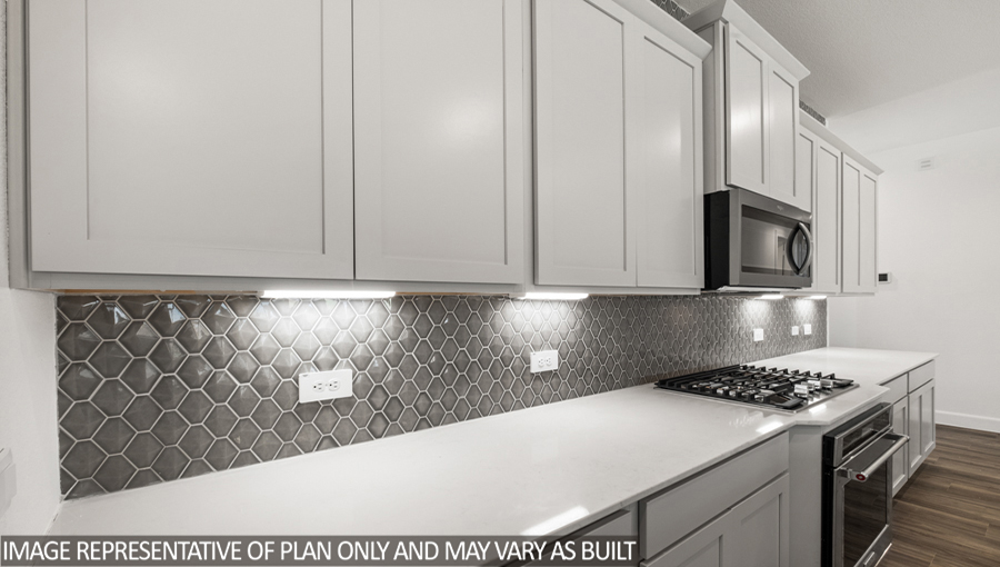 Kitchen with pretty cabinets and tile backing on wall.