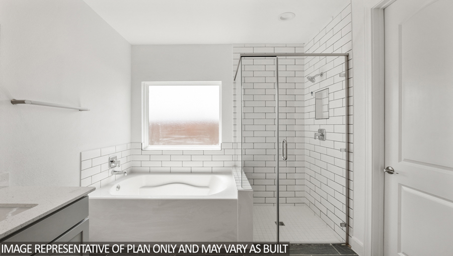 Primary bathroom with a tile tub, a frosted window, and a standing shower with a glass door.