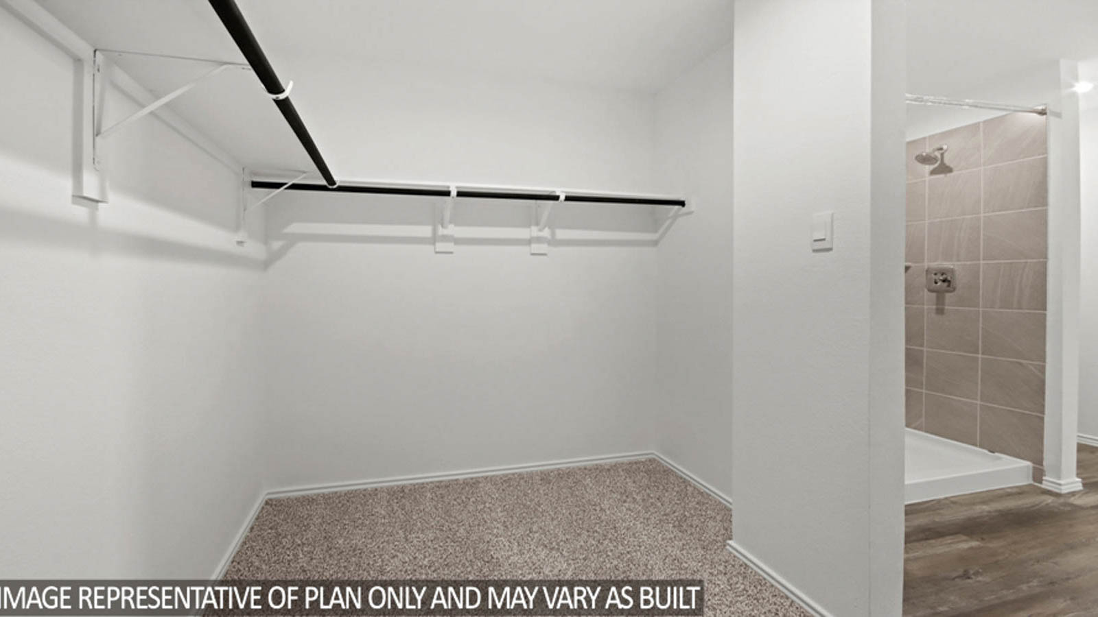 Primary bedroom walk-in closet with carpet flooring and overhead storage space.