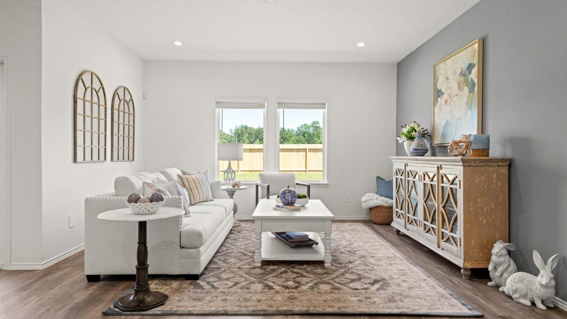 Staged living room with vinyl flooring and bright windows.