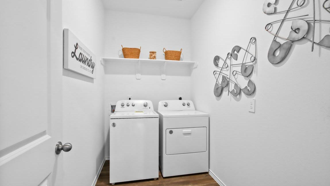 Utility room with vinyl flooring and overhead storage space.