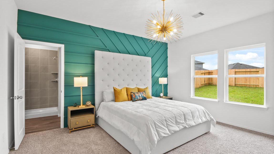 Primary bedroom with carpet flooring and bright windows.