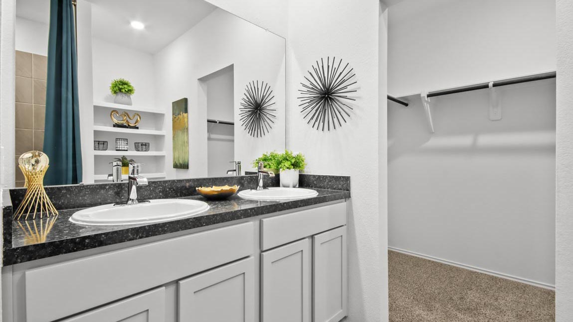 Primary bathroom with a double sink and a spacious walk-in closet.