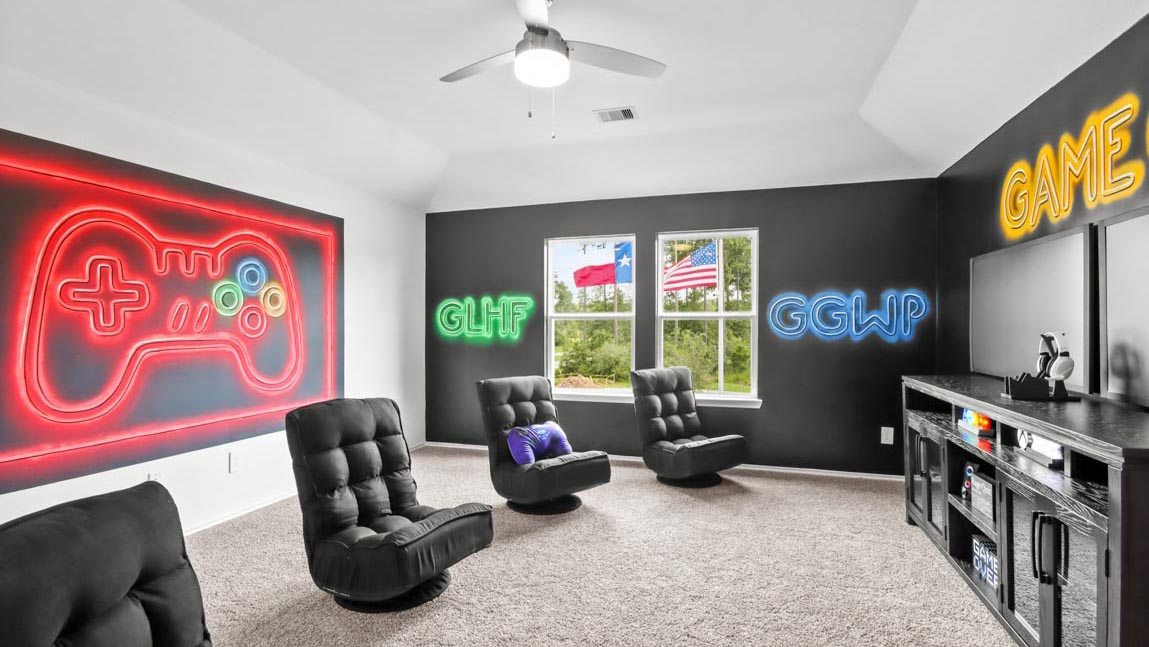 Upstairs game room with carpet flooring and bright windows.