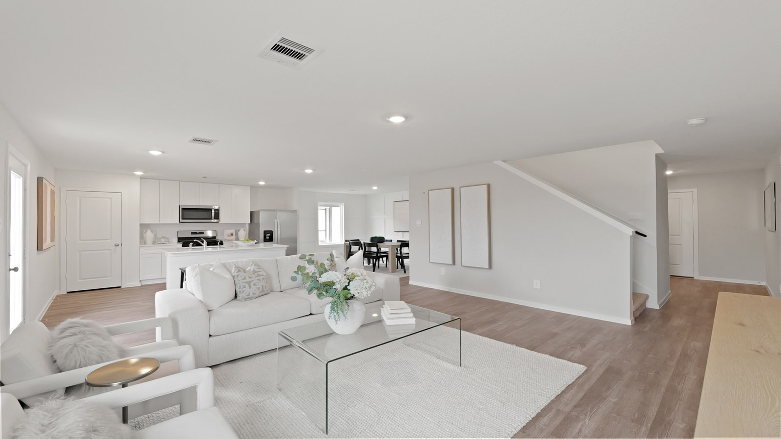 Open concept living and dining area with vinyl flooring and bright windows.