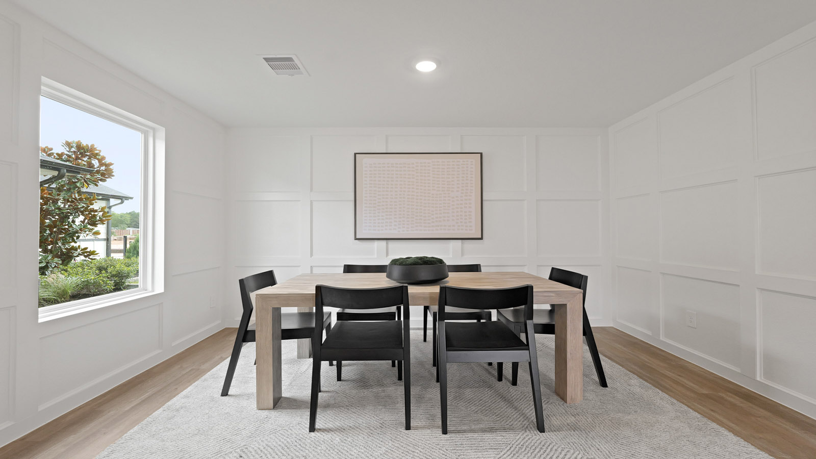 Dining area with vinyl flooring and a bright window.