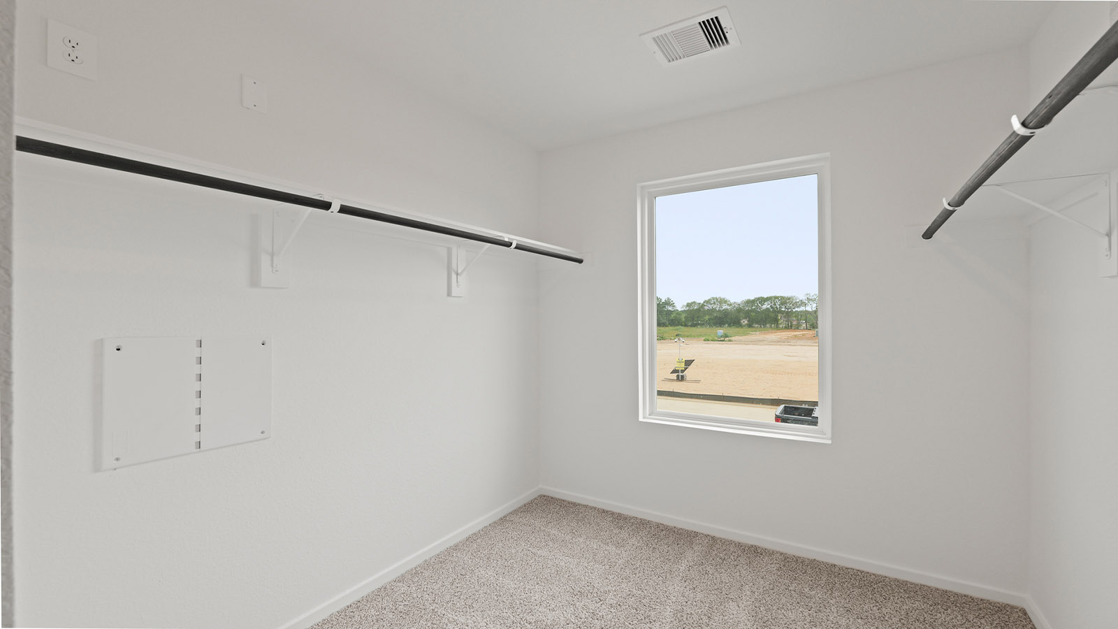 Spacious walk-in closet with carpet flooring and a bright window.