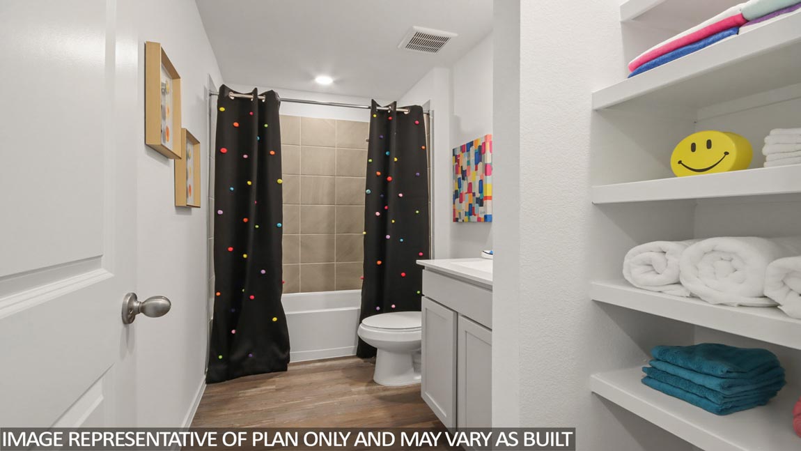 Staged secondary bathroom with vinyl flooring, a linen nook, and a tile tub/shower combo.