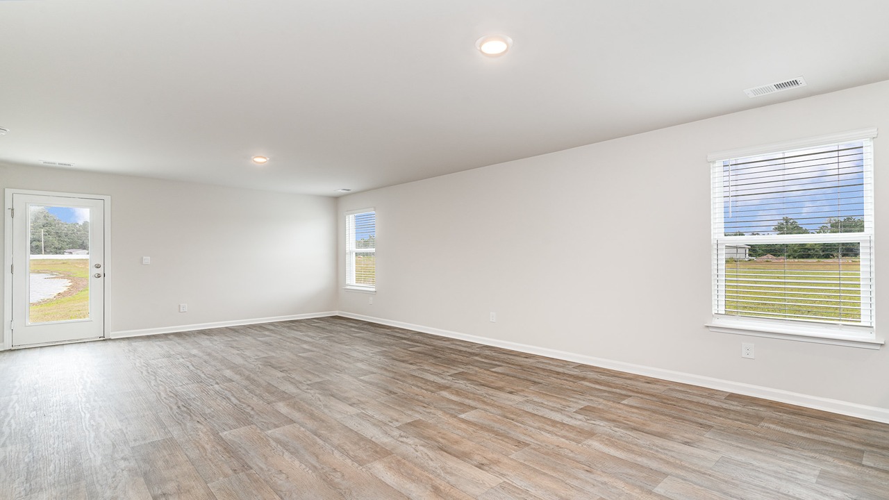 Open concept living and dining area with vinyl flooring and bright windows.