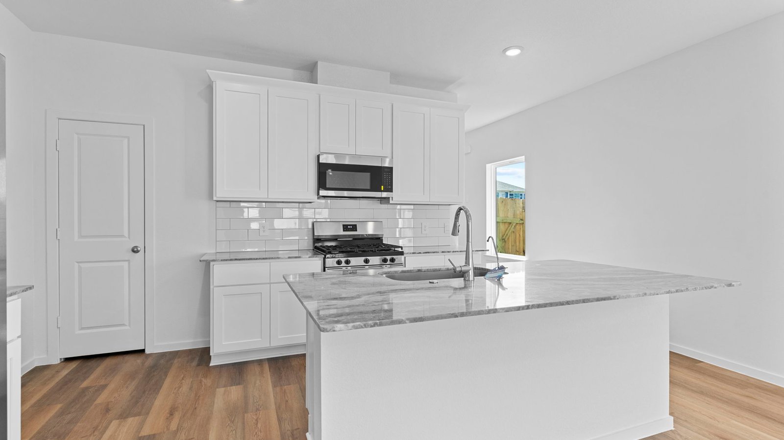 kitchen with white cabinets, stainless steel appliances and island with sink
