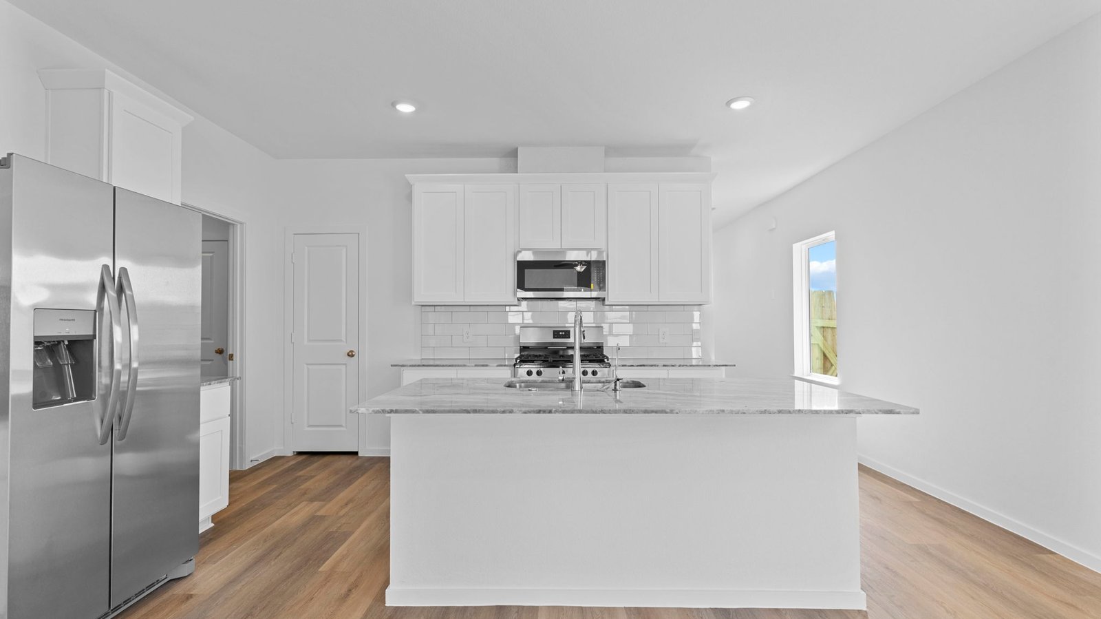 kitchen with white cabinets, stainless steel appliances and island with sink