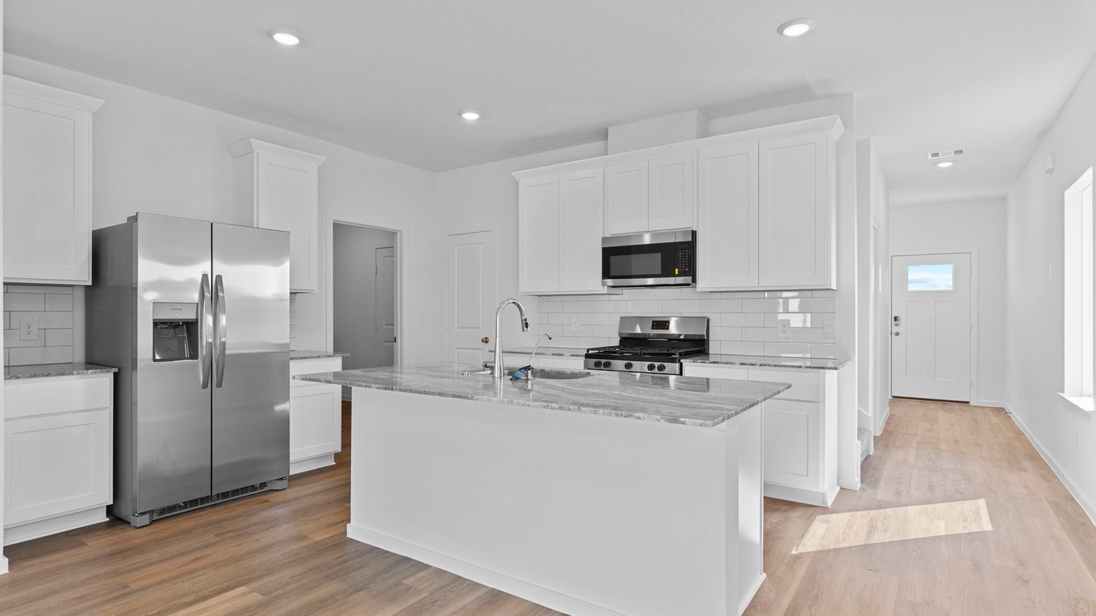 kitchen with white cabinets, stainless steel appliances and island with sink