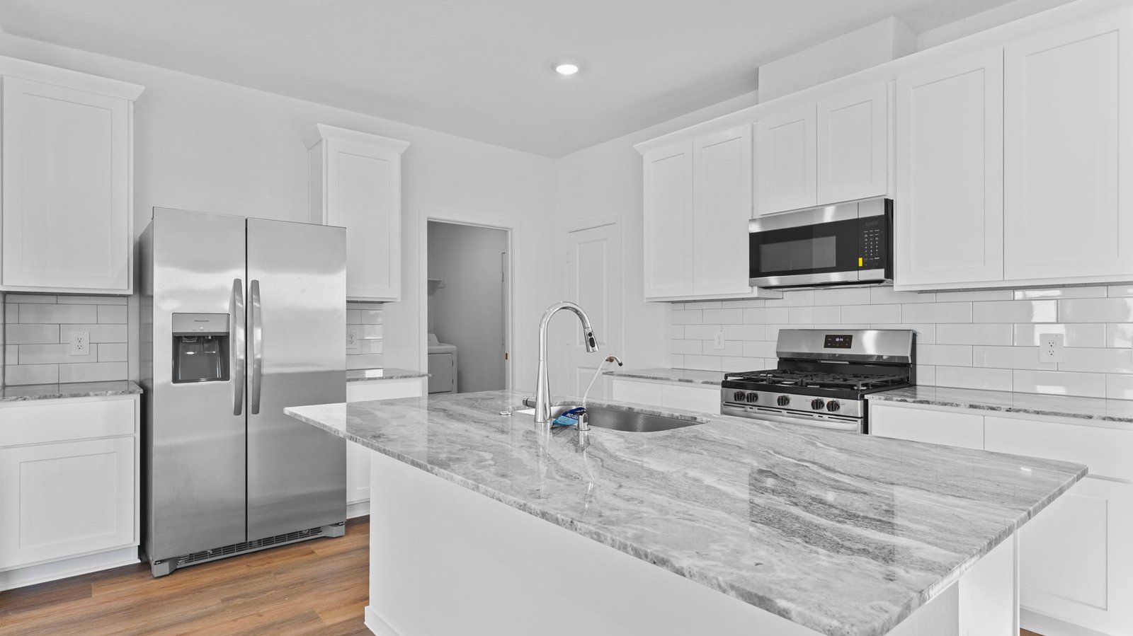 kitchen with white cabinets, stainless steel appliances and island with sink
