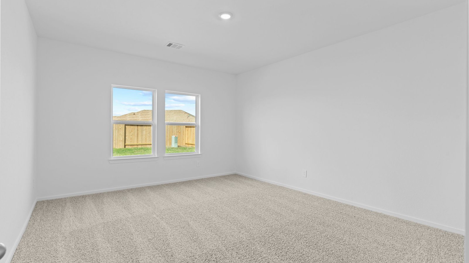 primary bedroom with two windows and carpet