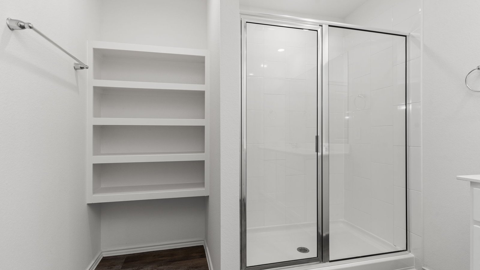 primary bathroom with dial vanity sinks, standing shower, and storage shelves