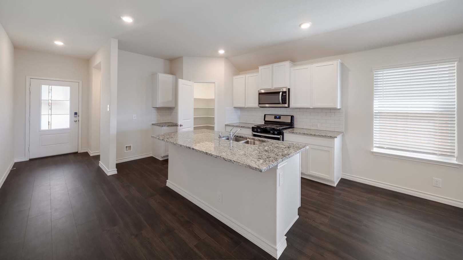 Open concept kitchen with stainless steel appliances, shaker style cabinets, and elevated finishes