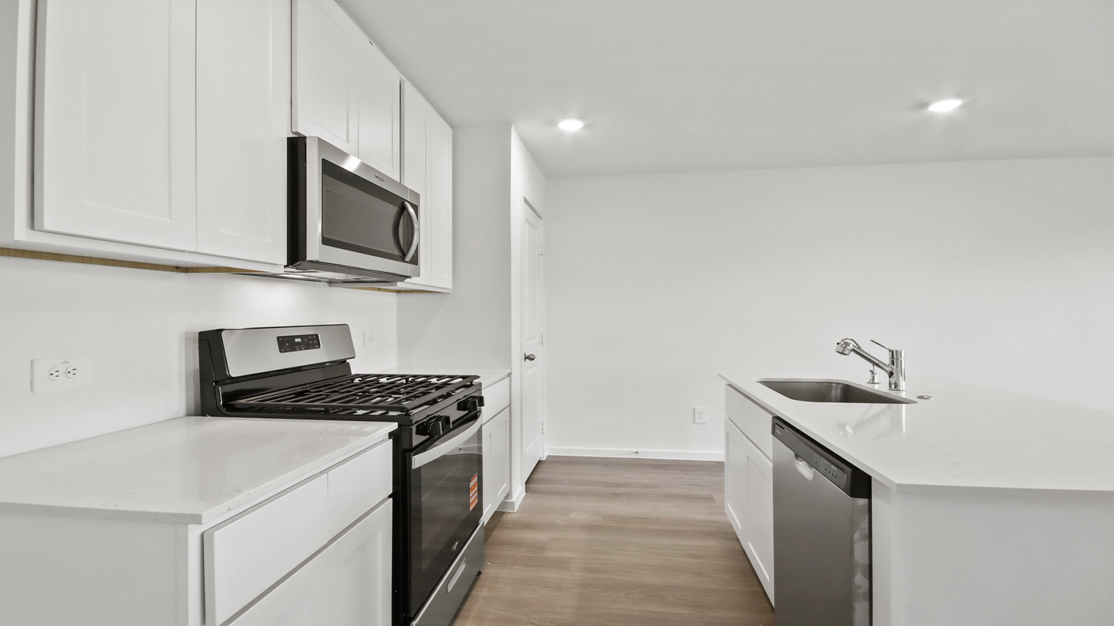 Open concept kitchen with stainless steel appliances, shaker style cabinets, and elevated finishes