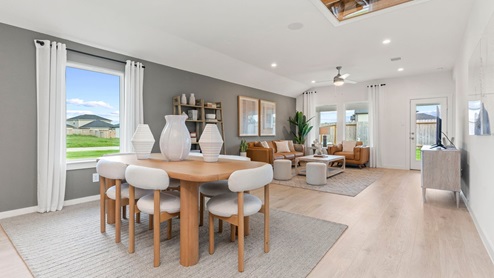open dining area with windows and open concept kitchen with white cabinets