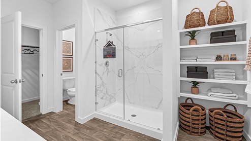 primary bathroom with walk-in shower, shelves and primary closet