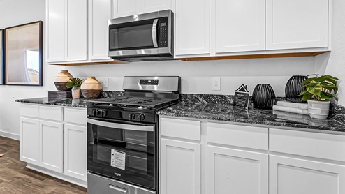 kitchen with gas range stove, microwave hood, white cabinets, granite countertops