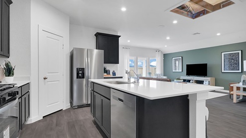 kitchen peninsula with black cabinets facing the living area