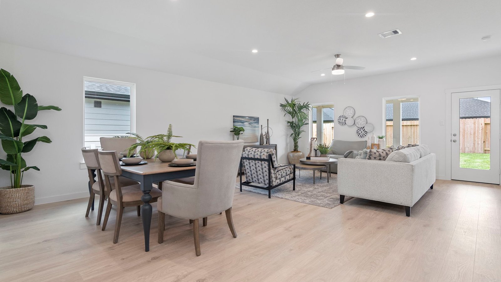 A cozy living room feature vinyl wood flooring and a view to the kitchen and dining area