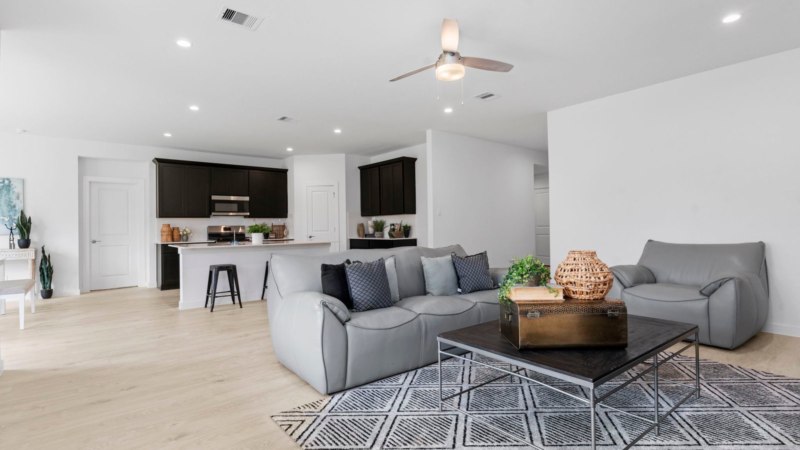 A cozy living room feature vinyl wood flooring and a view to the kitchen and dining area