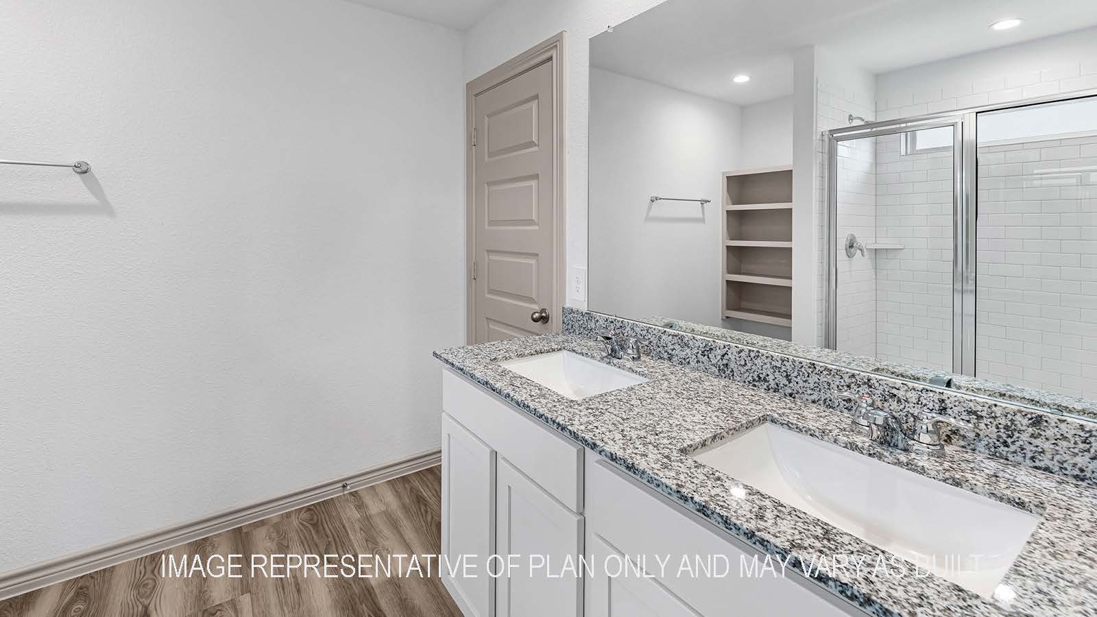 Camden primary bathroom with dual vanity sinks with granite countertops and mirror.