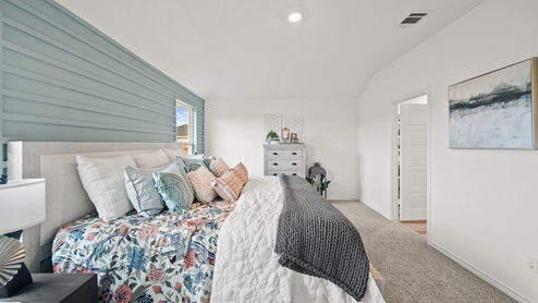 Reserve at Mallard Lakes model home primary bedroom with painted shiplap wall detail and furniture.