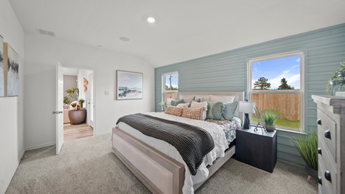 Reserve at Mallard Lakes model home primary bedroom with carpet flooring and view to backyard.