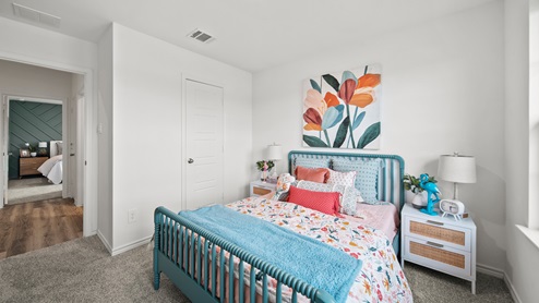 Reserve at Mallard Lakes model home secondary bedroom with colorful bedding accents and carpet flooring.