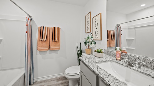 Reserve at Mallard Lakes model home secondary bathroom with gray cabinets and granite countertops.