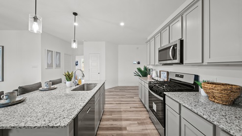 Reserve at Mallard Lakes model home kitchen with granite countertops and gray cabinets and ample storage options.