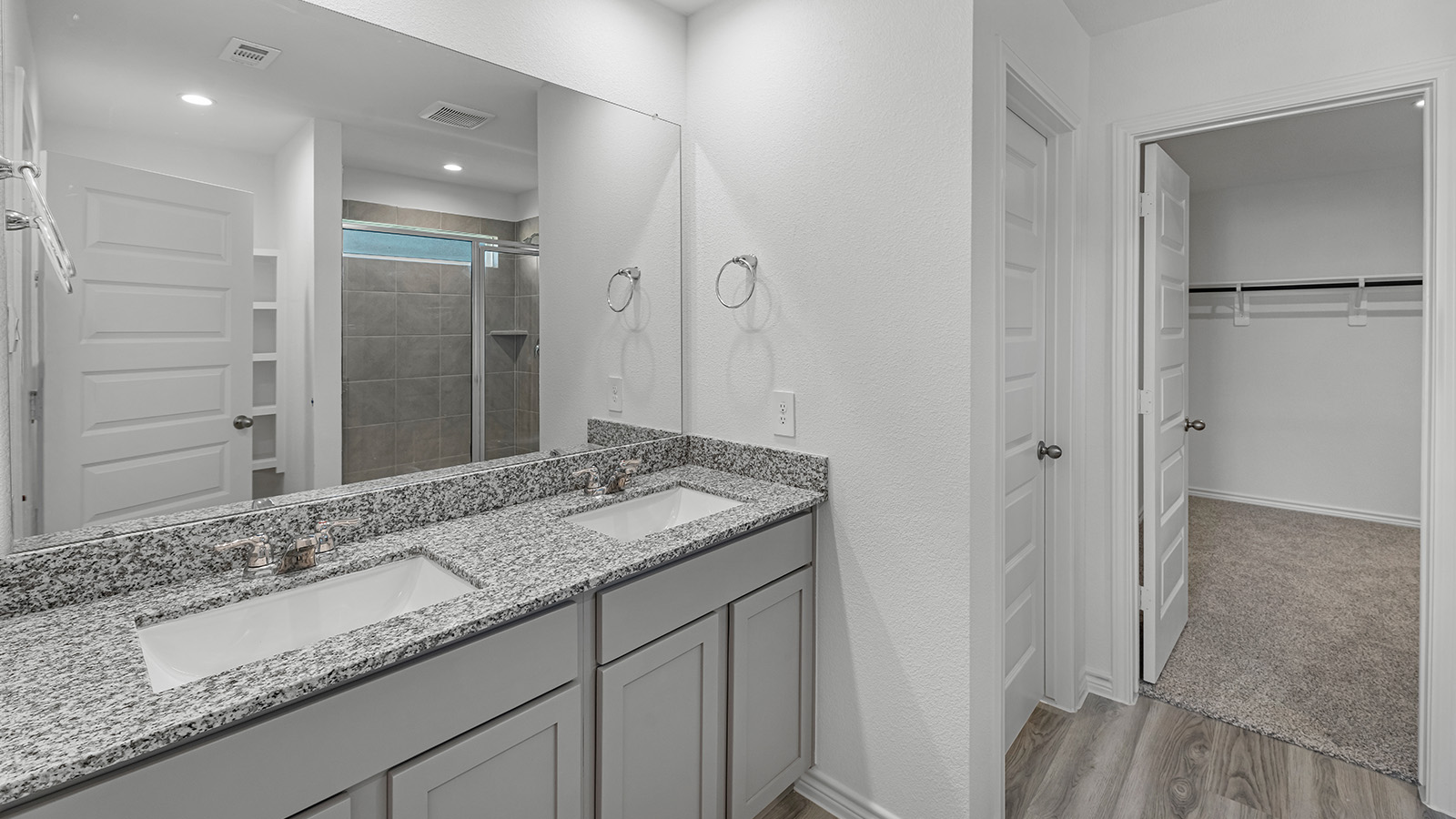 Harris primary bathroom with double vanity sink and view of primary walk-in closet.