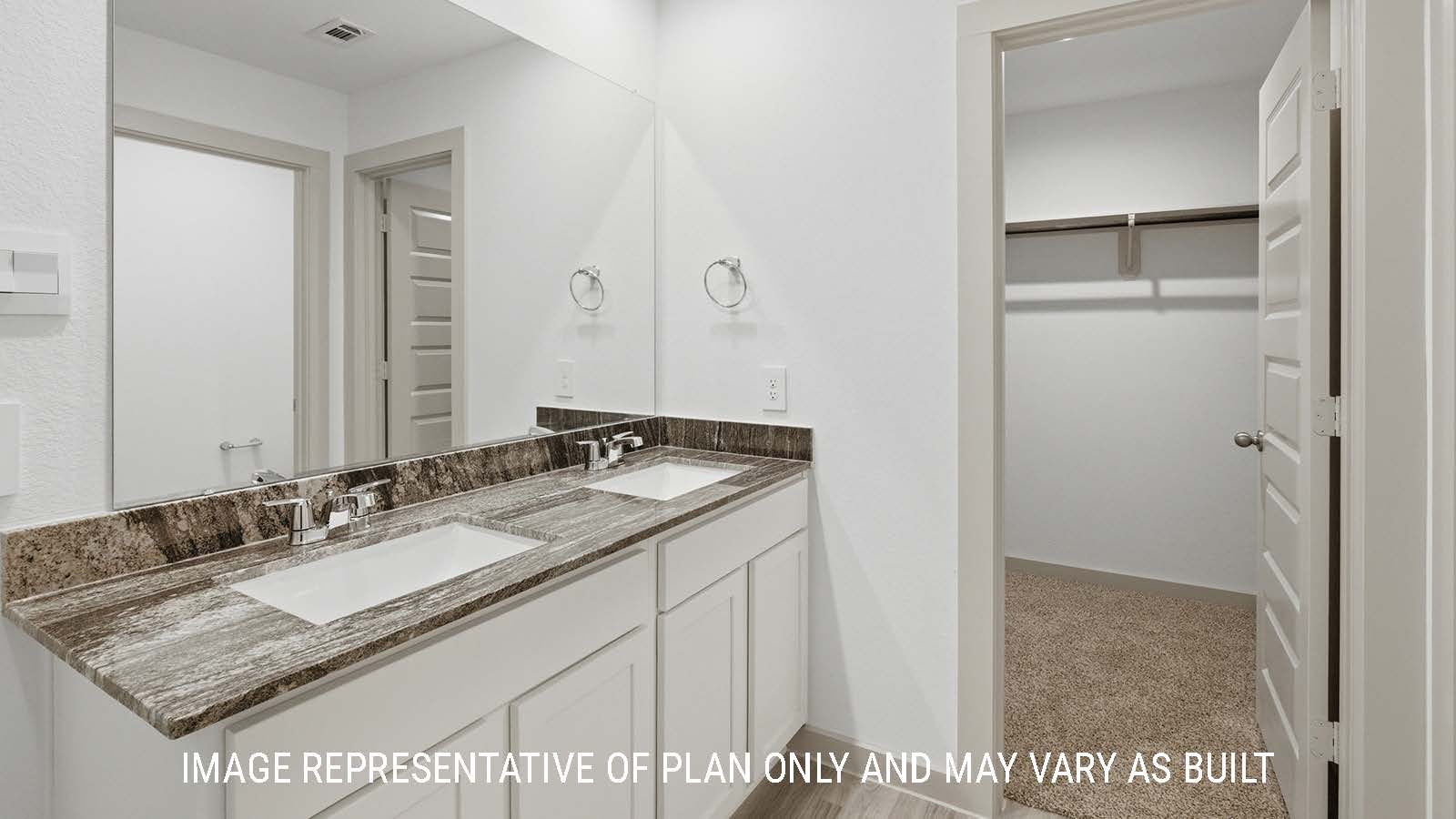 Bellvue primary bathroom with double vanity sink and view of primary bedroom walk-in closet.